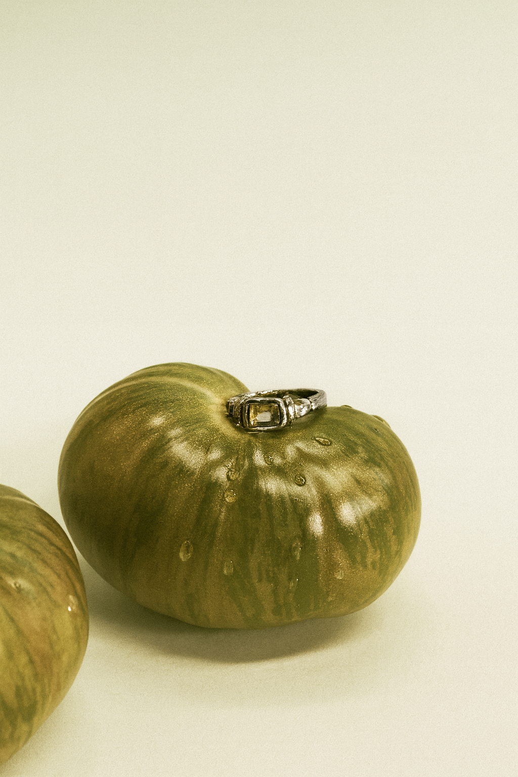 Green tomato with a ring on a beige background