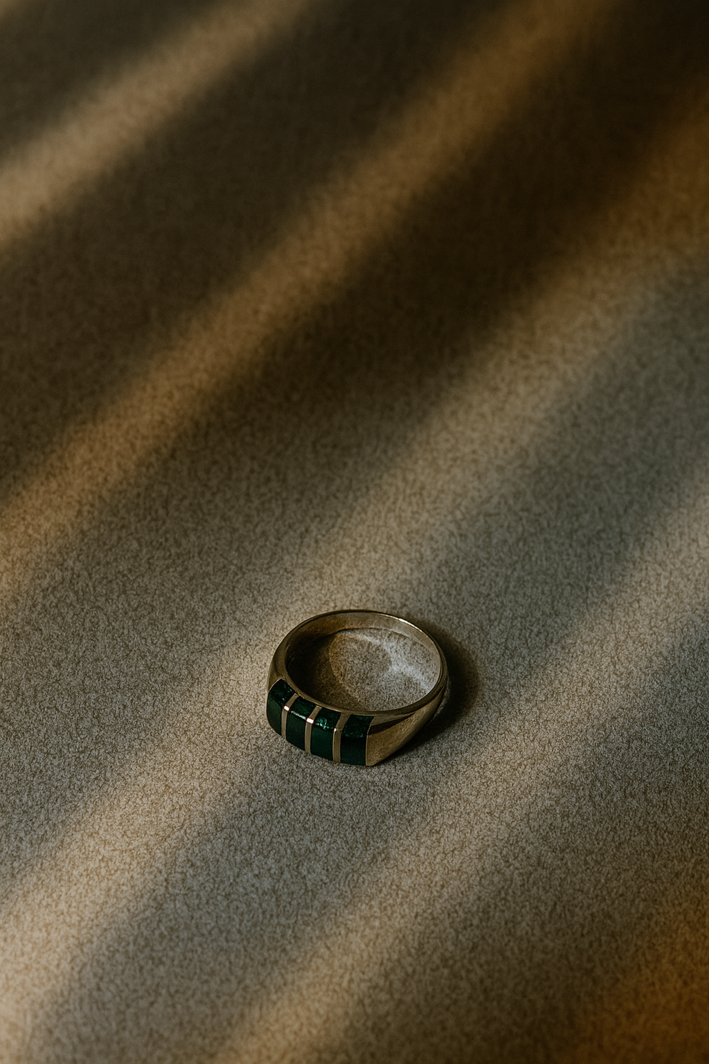 Ring with green gemstones on a textured brown surface