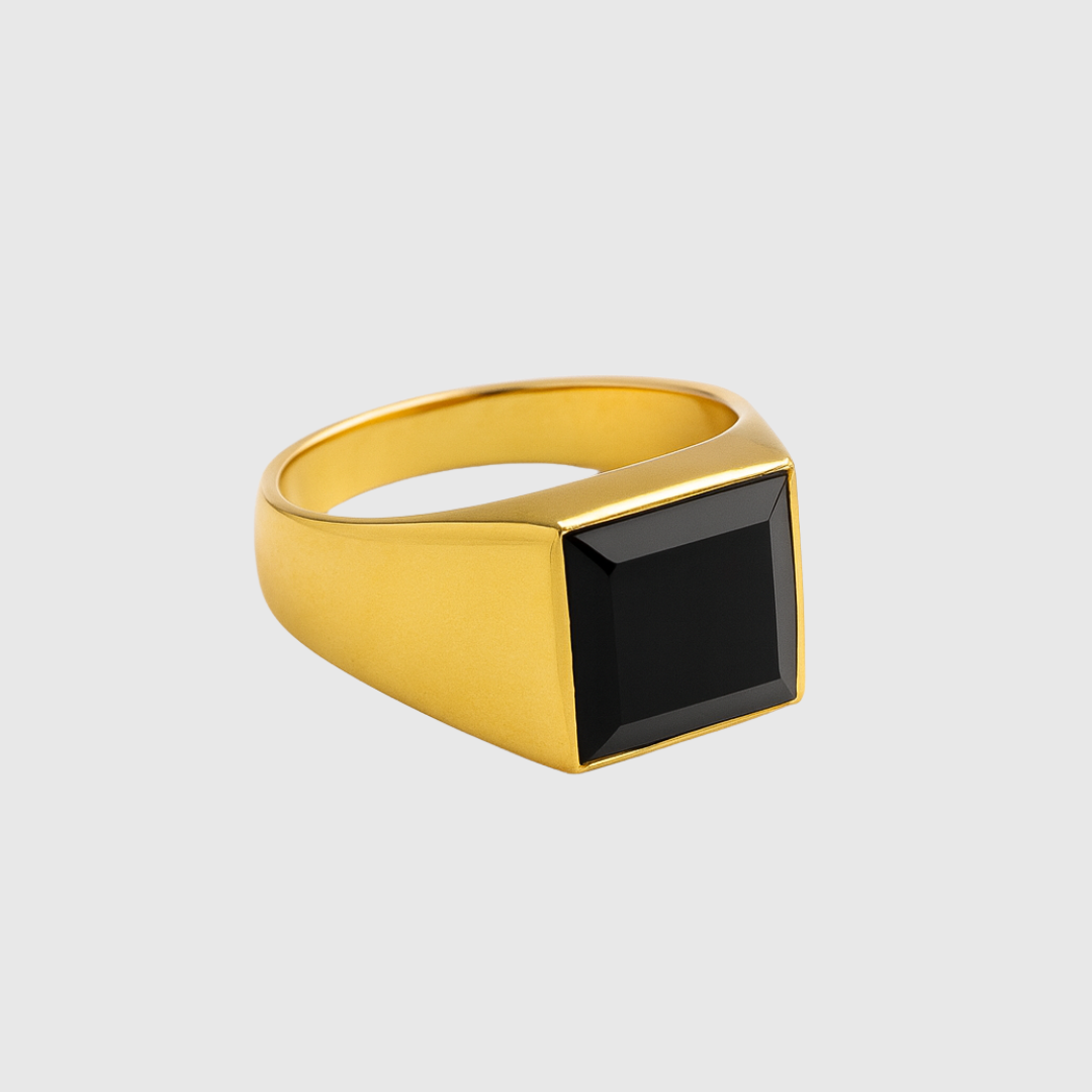 Gold ring with a black gemstone on a light gray background