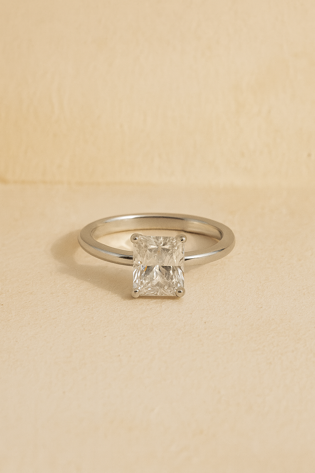 Silver ring with a square-cut diamond on a beige background